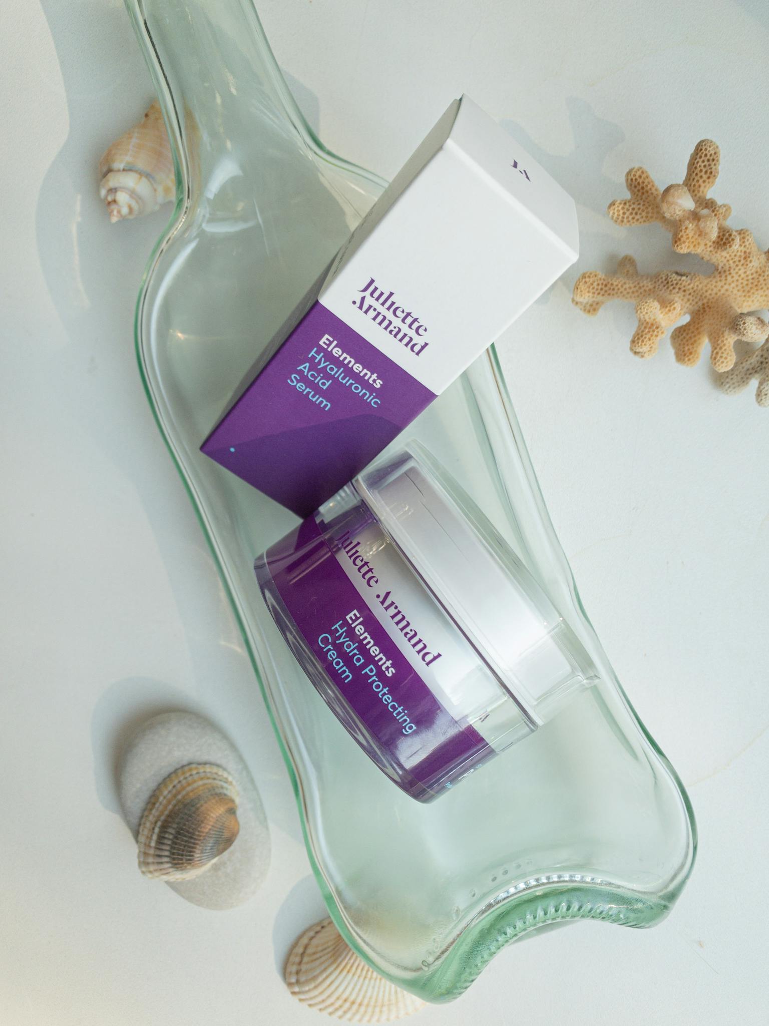 Hyaluronic serum and cream displayed with seashells, enhancing beauty.