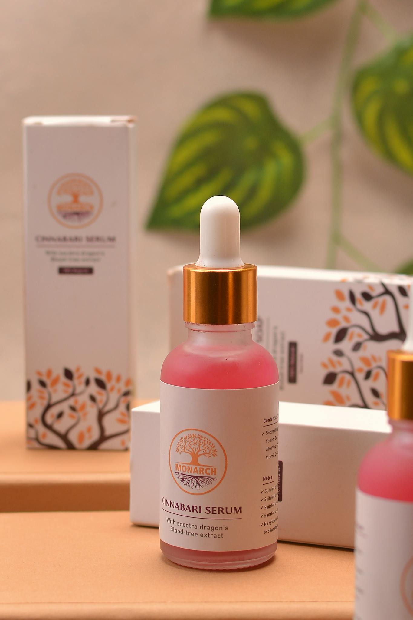 Stylish presentation of Cinnabari serum bottles with vibrant packaging and a touch of greenery.